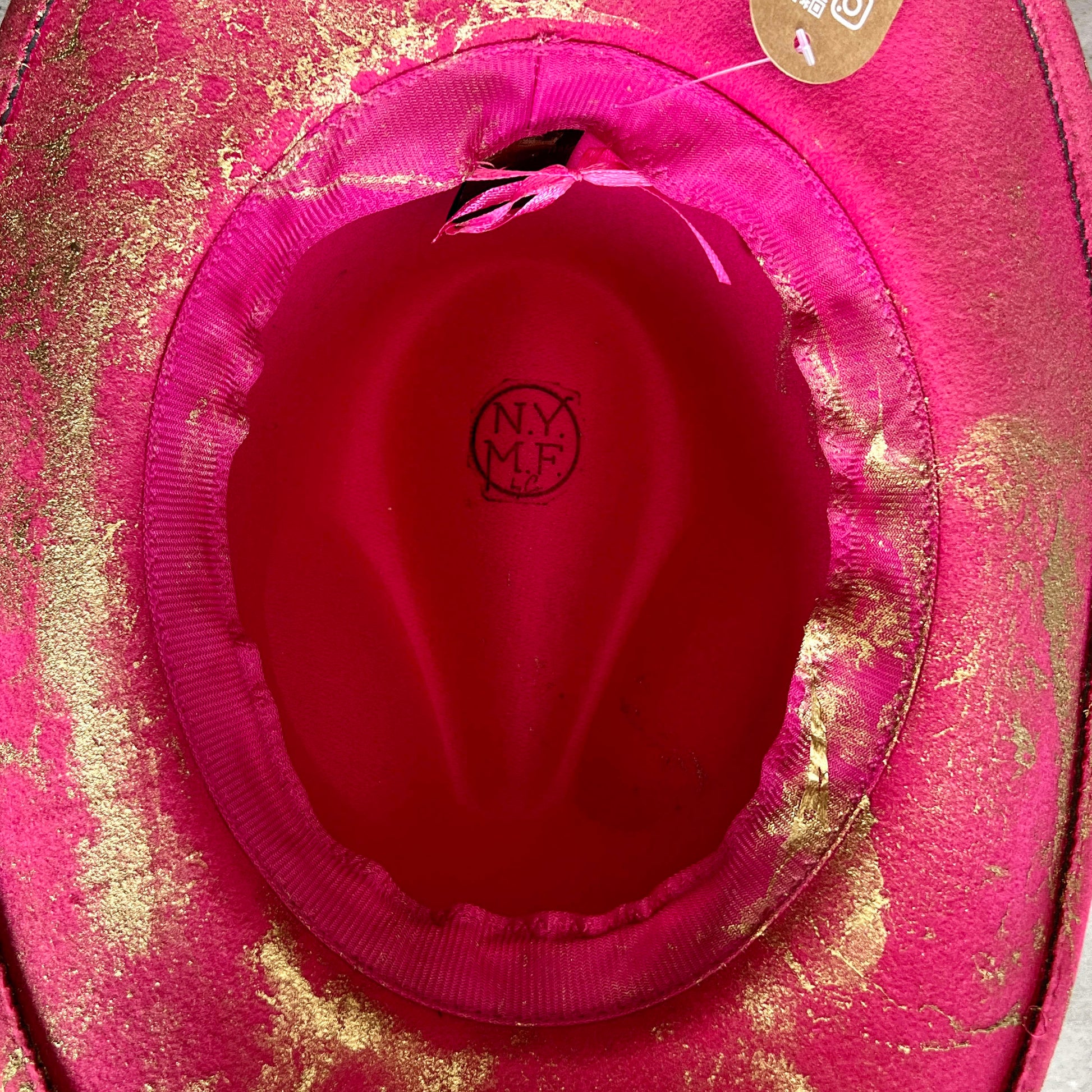 Hot pink cowboy hat displaying internal drawstring for adjustable sizing.
