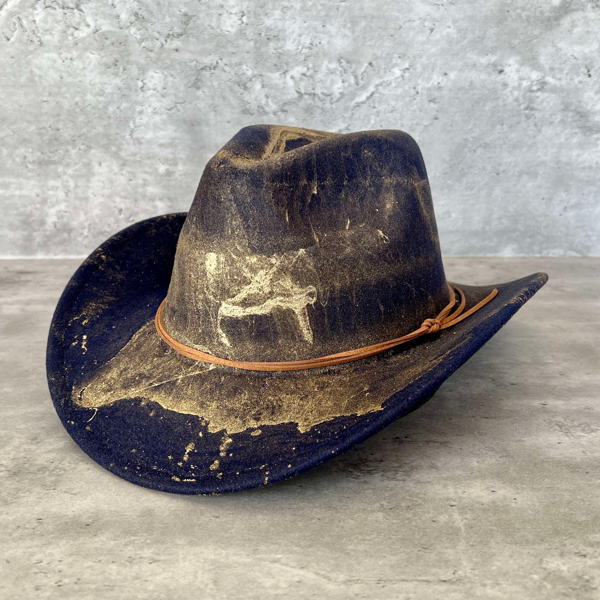 Navy blue western cowboy hat painted with gold marbling. Has light brown faux suede cord hat band.