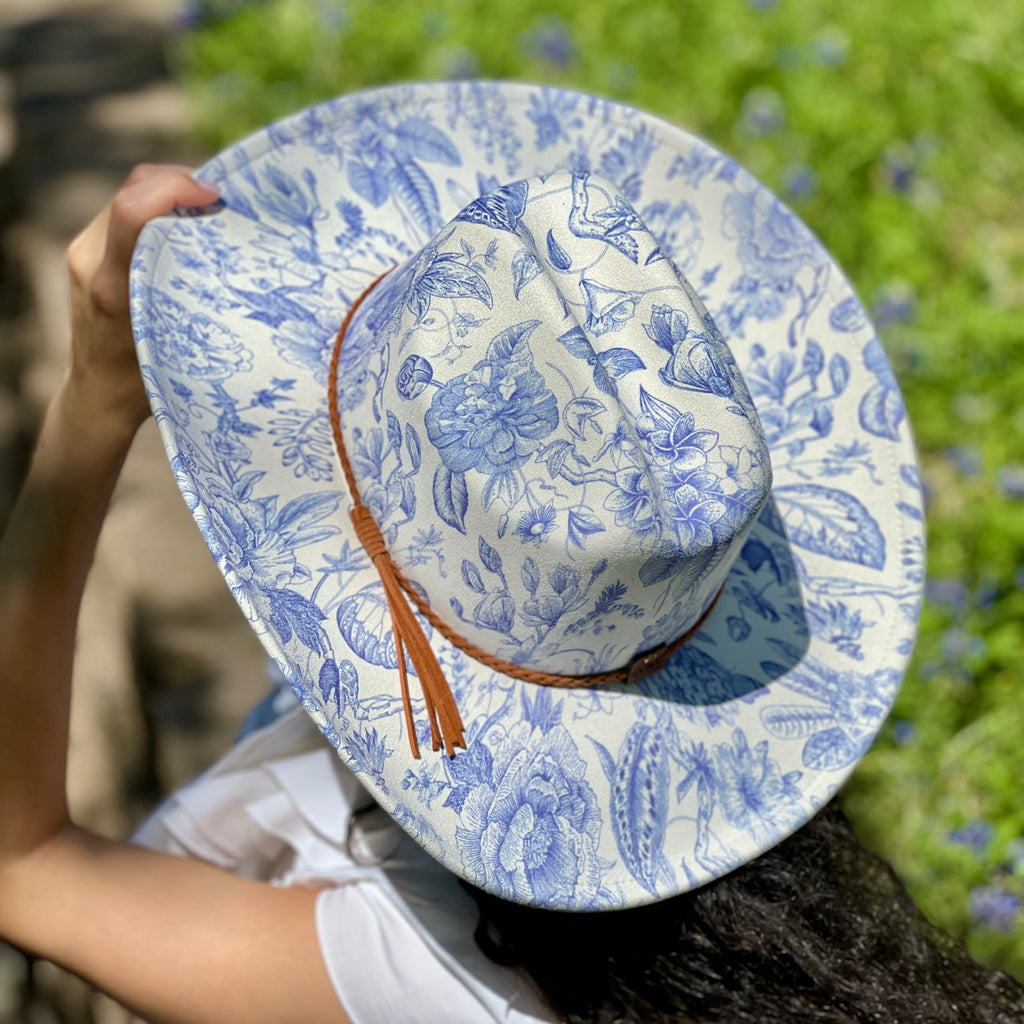 Blue and white patterned hat held by a person with a blurred natural background