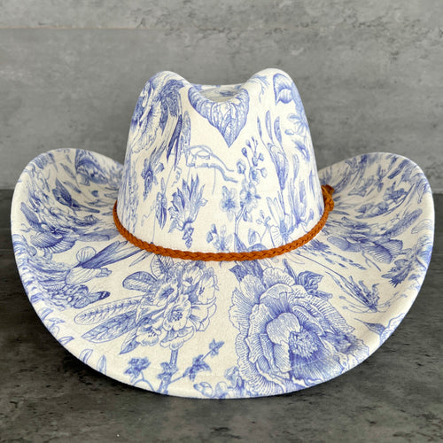 Cowboy hat with blue floral pattern on a gray surface