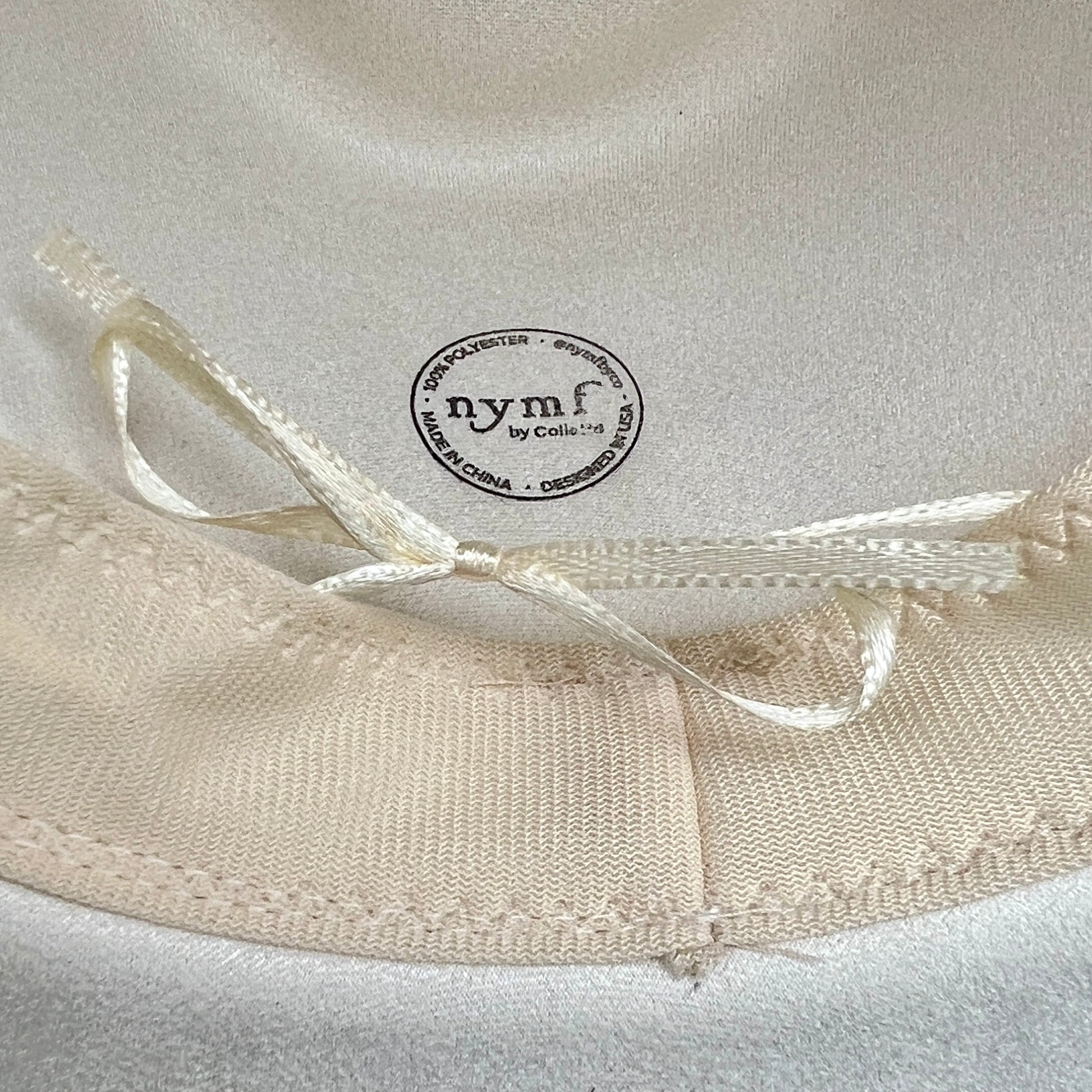 Close-up of a white satin bow with 'nymf' branding on a white background