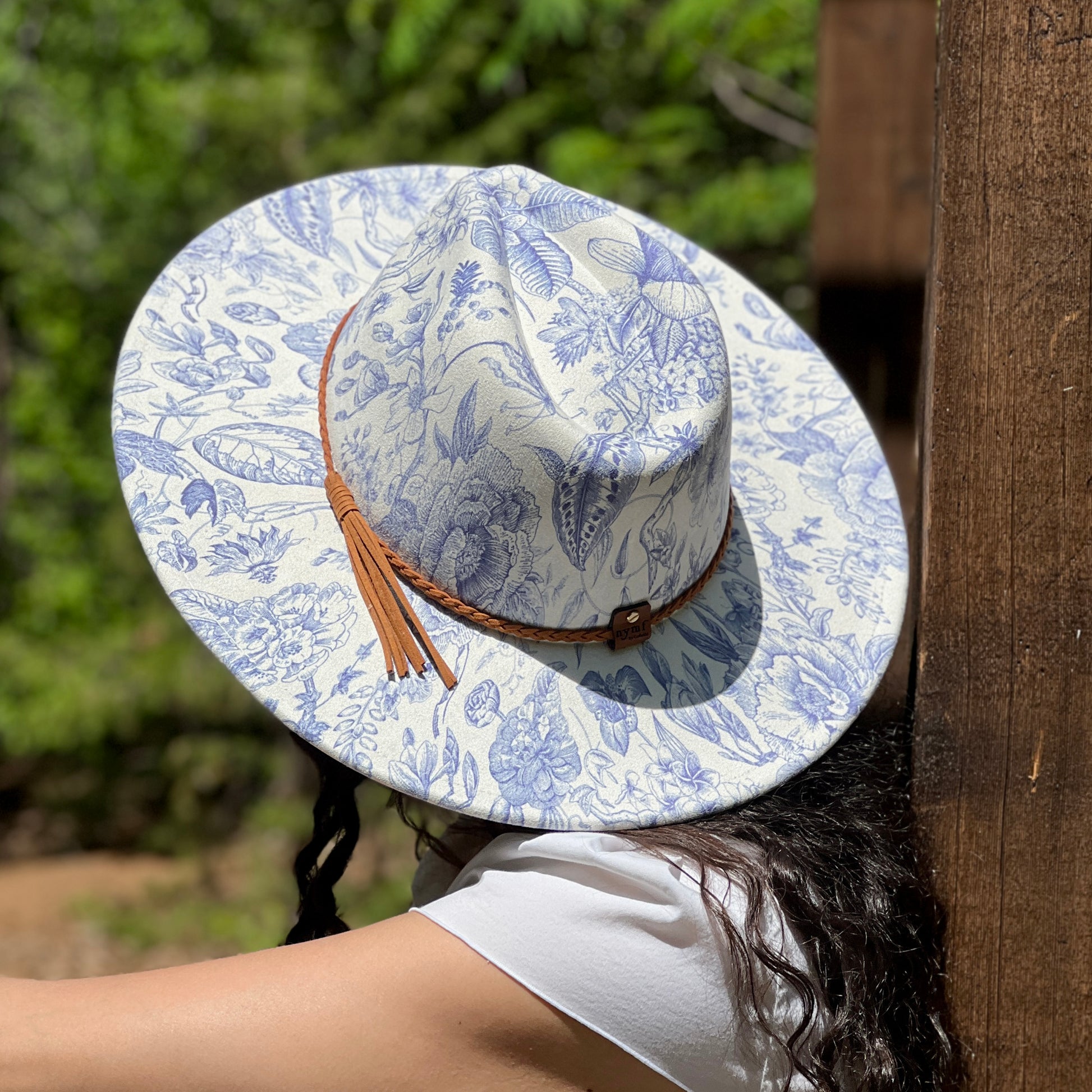 Person wearing a blue and white patterned hat with a brown tassel outdoors.