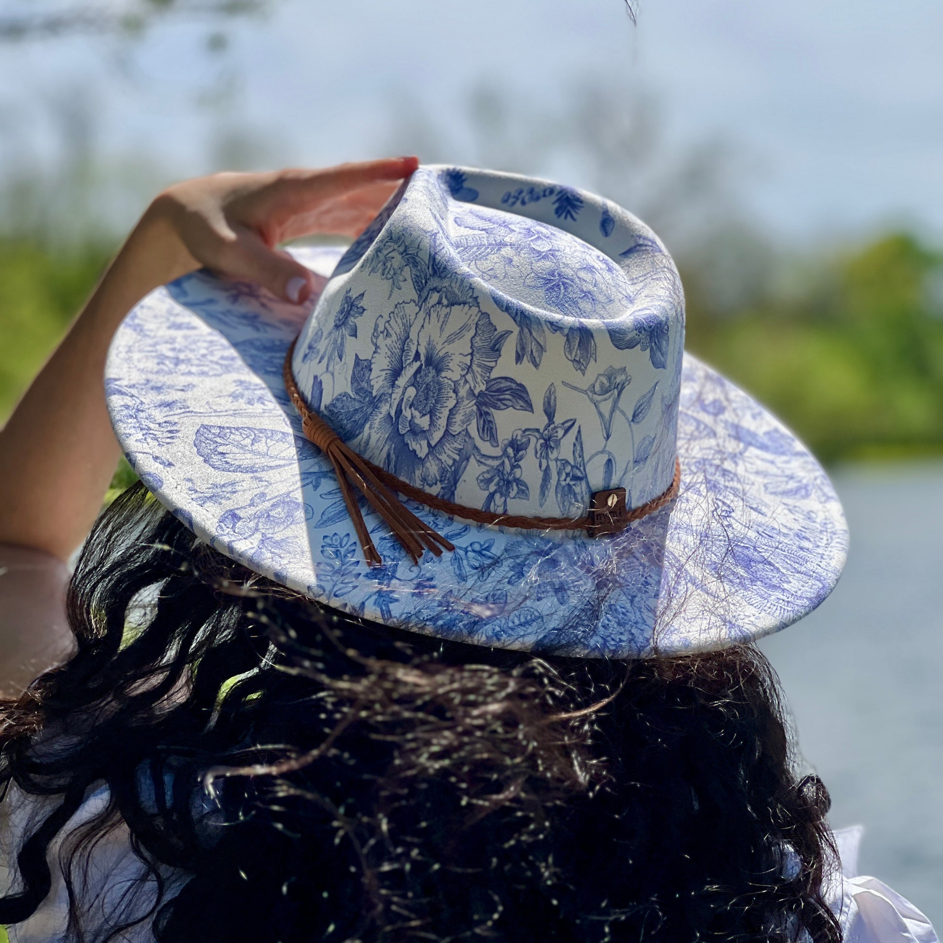 Person wearing a blue floral-patterned cowboy hat outdoors