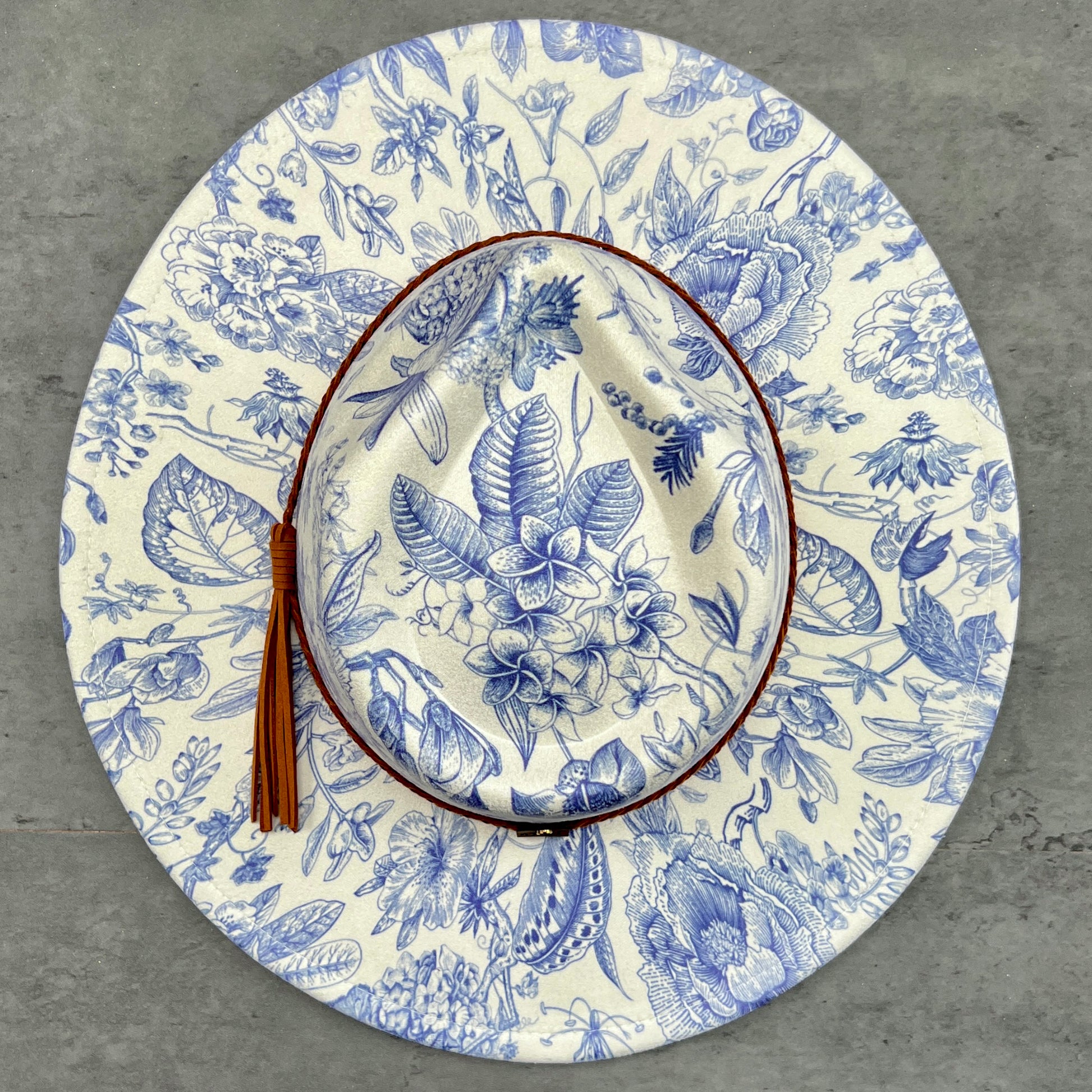 Floral-patterned hat with a tassel on a gray surface