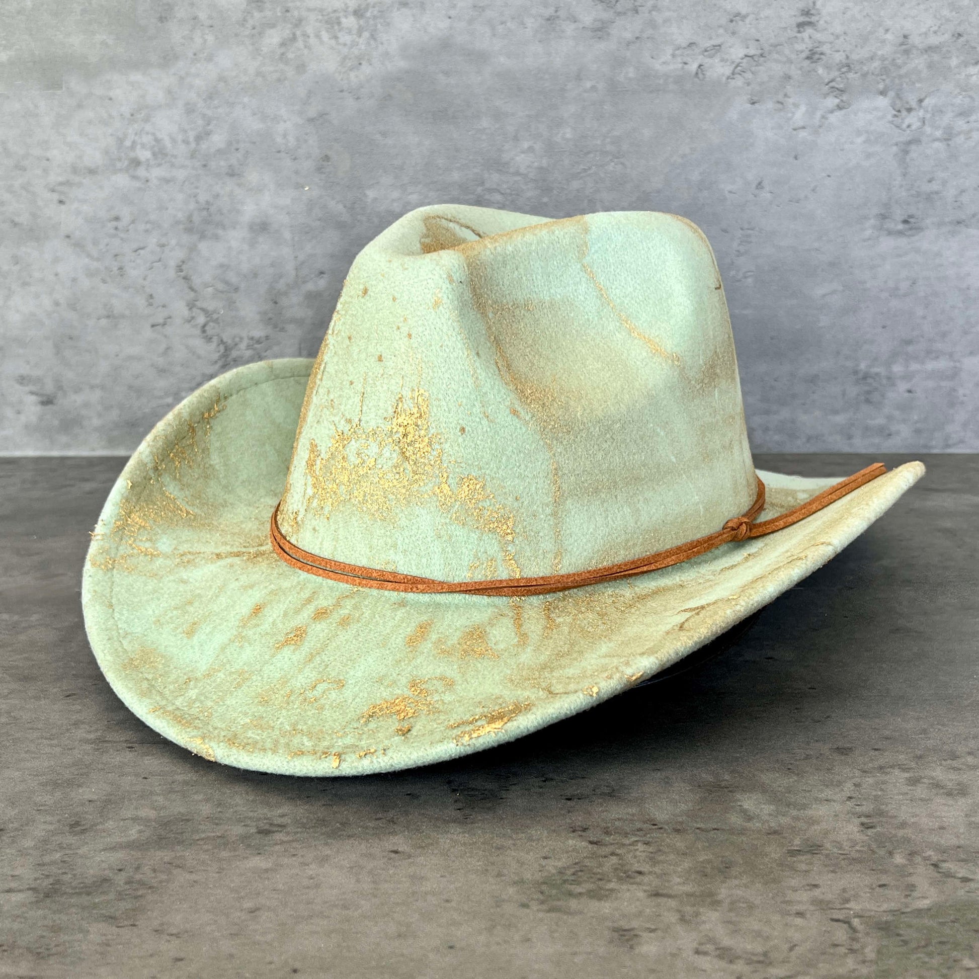 Mint seafoam green western cowboy hat painted with gold marbling. Has light brown faux suede cord hat band. 