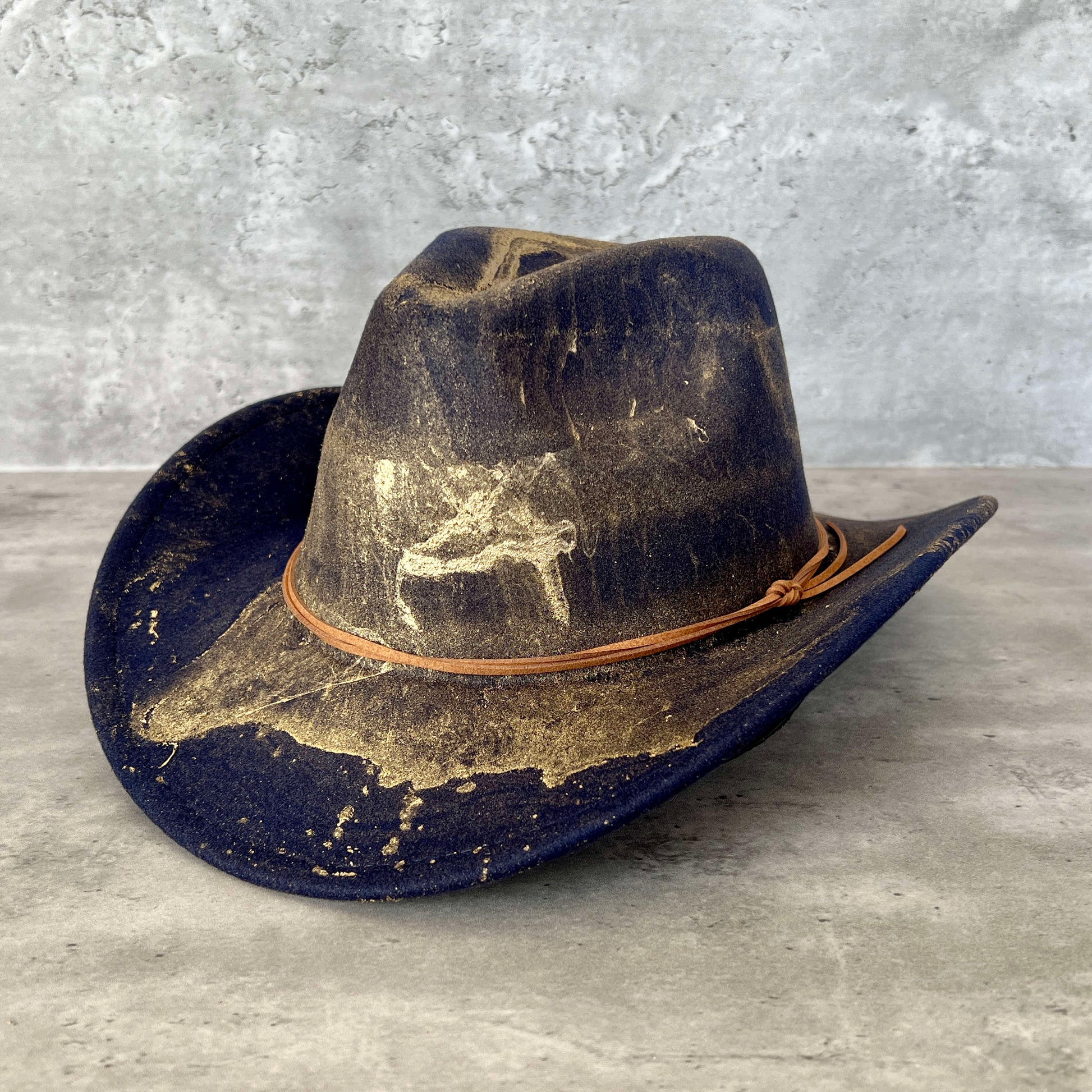 Navy blue western cowboy hat painted with gold marbling. Has light brown faux suede cord hat band. 