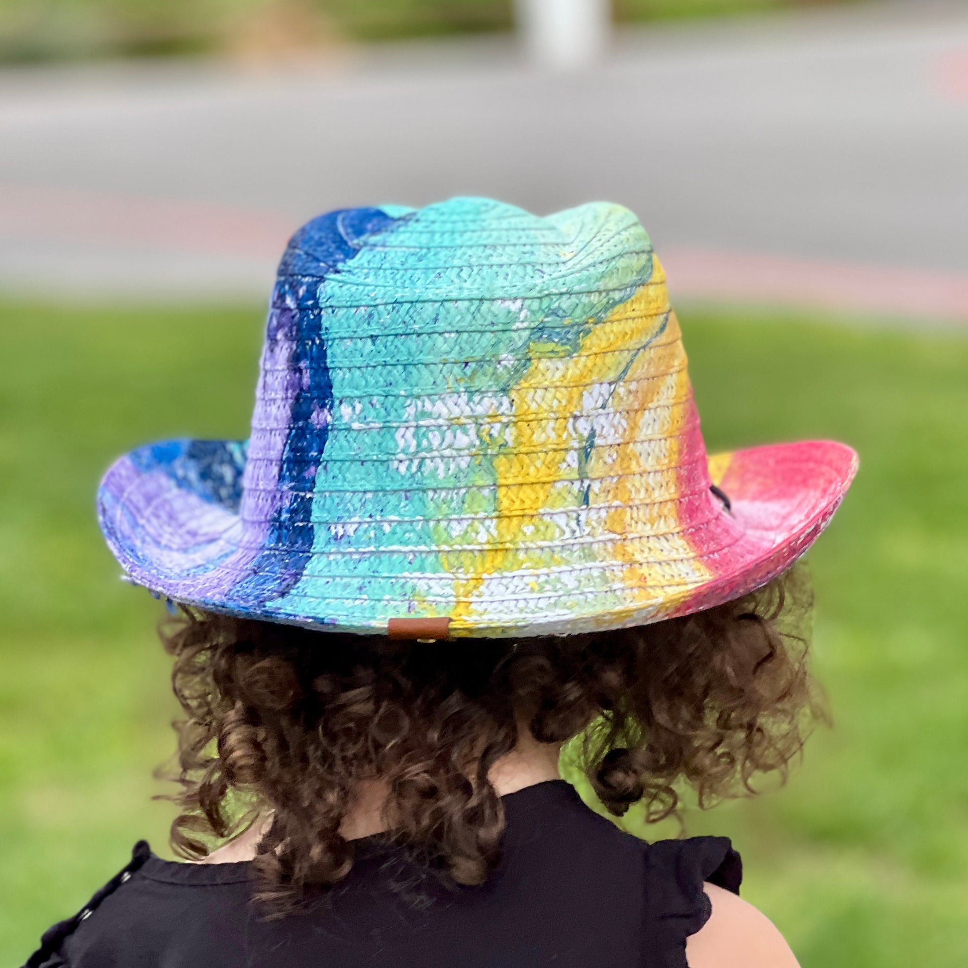 Person wearing a colorful straw hat with a blurred green background