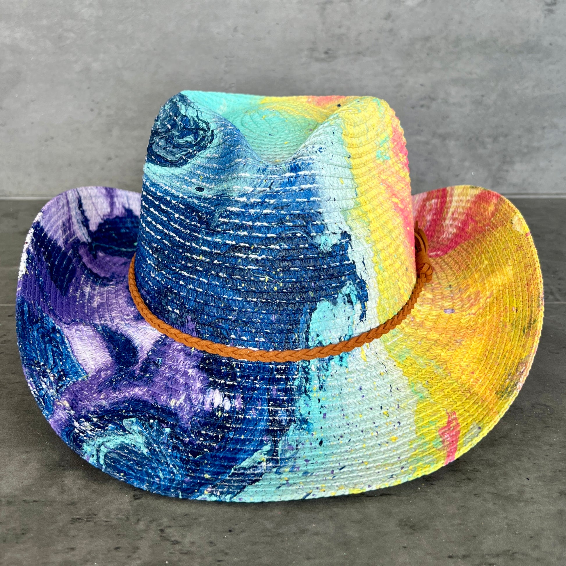 Colorful cowboy hat with a multicolored band on a gray surface