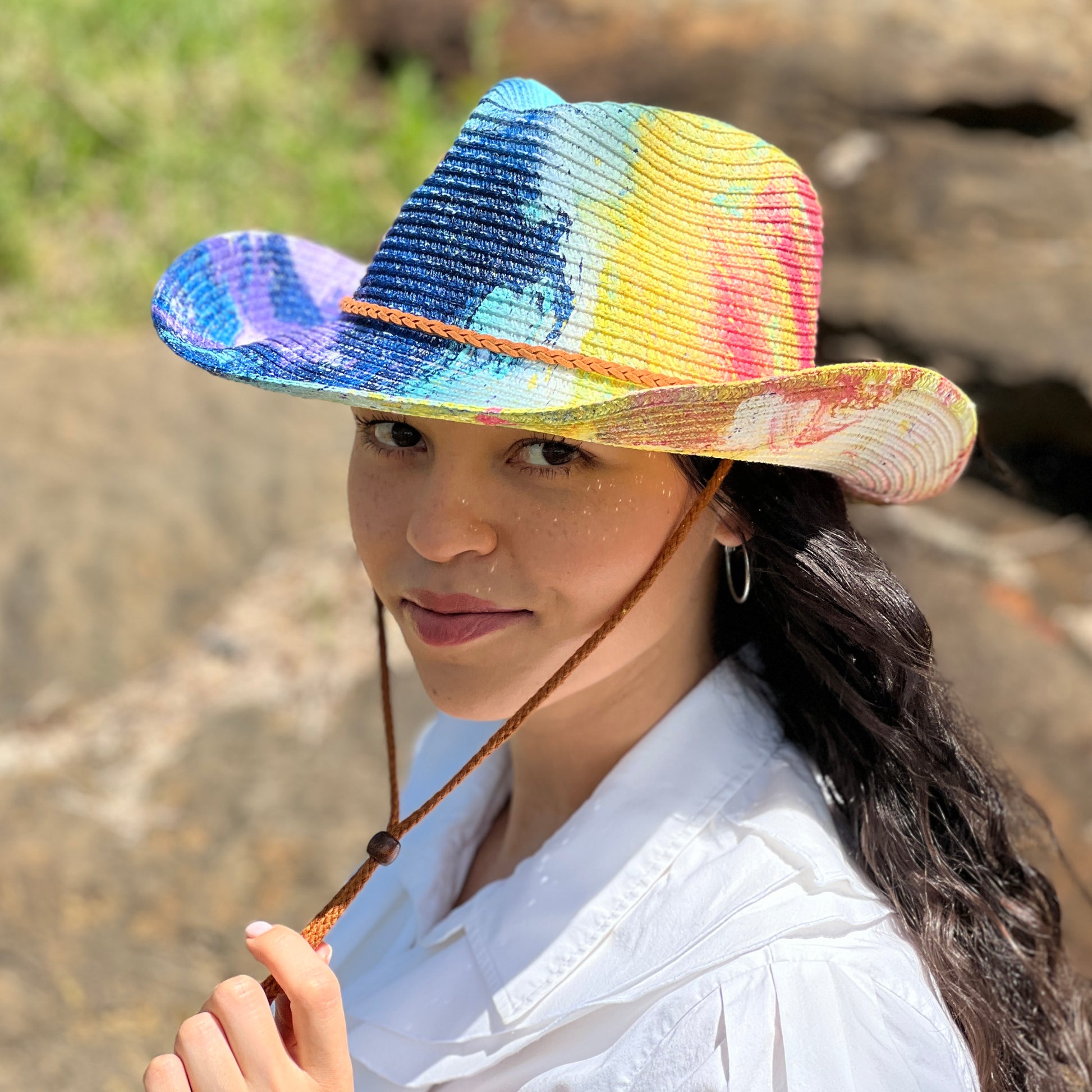 Person wearing a colorful straw hat with a blurred natural background