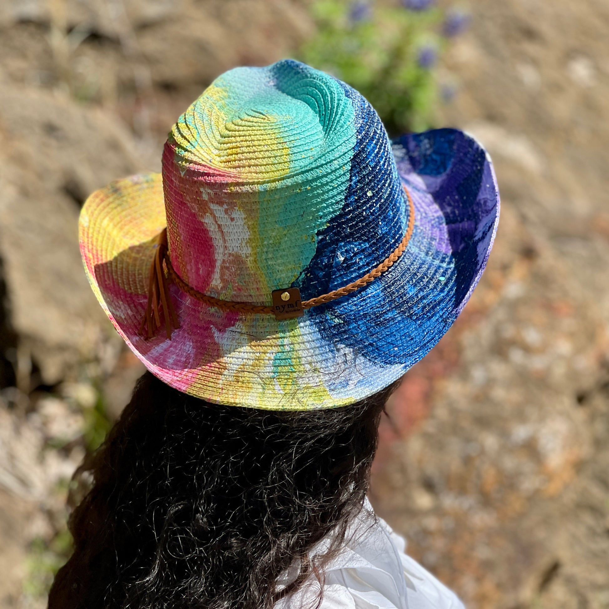 Colorful straw hat with a tassel worn by a person outdoors.