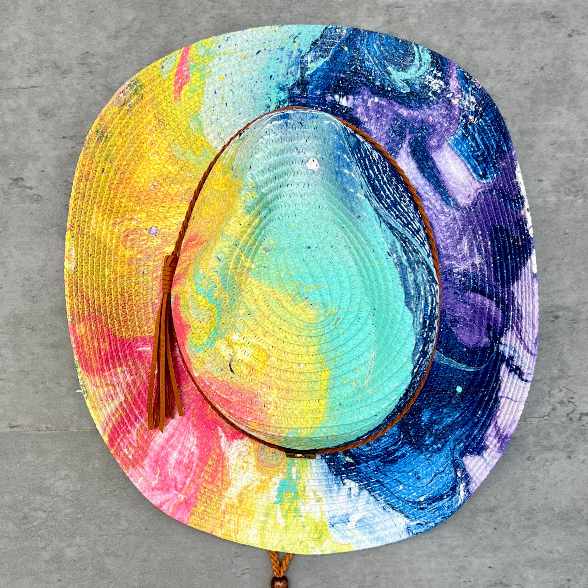 Colorful straw hat with a tassel on a gray surface
