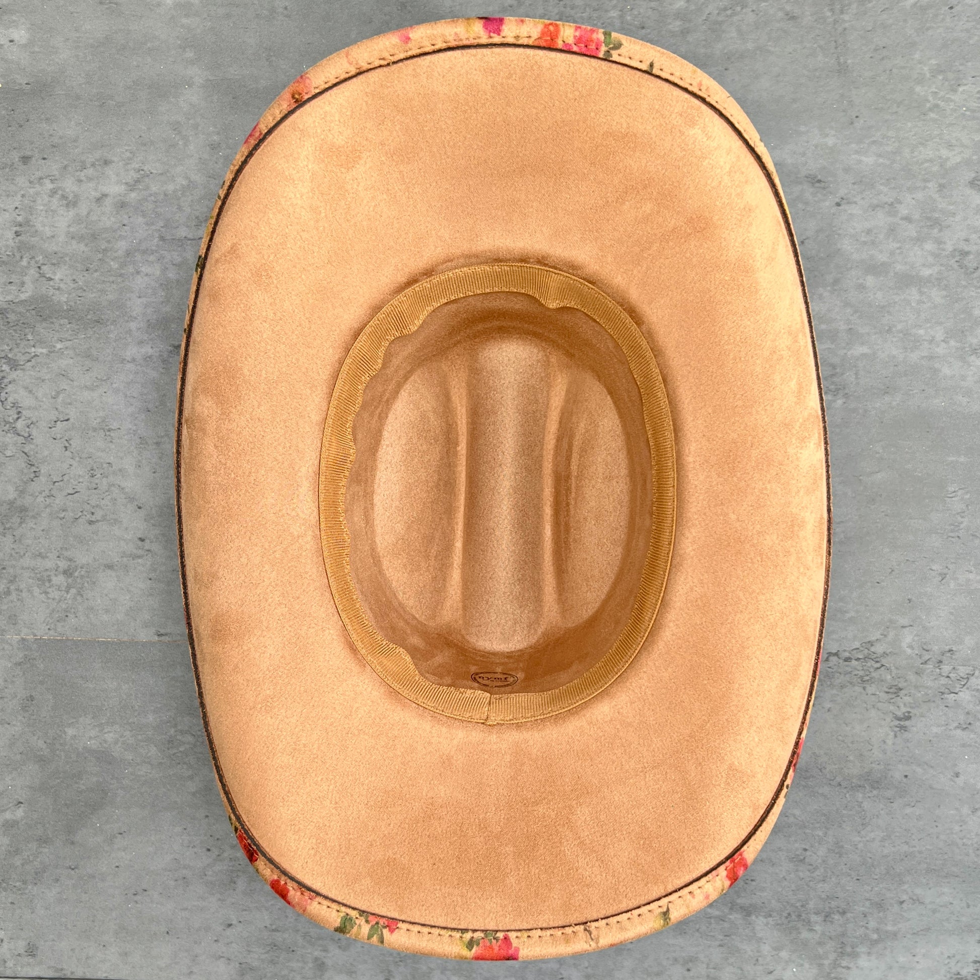 Tan suede hat base placed on a gray textured surface.