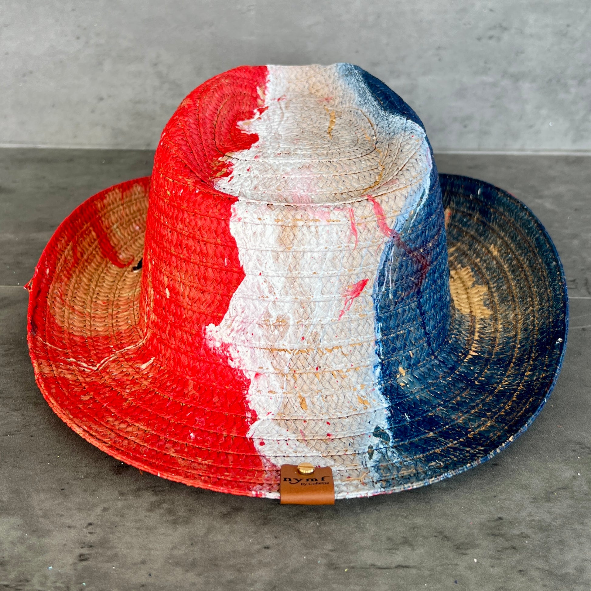 Colorful straw hat with red, white, and blue stripes on a gray surface