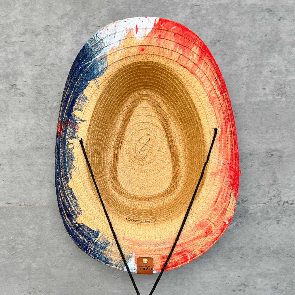 Colorful straw hat with a gradient from blue to red on a gray surface