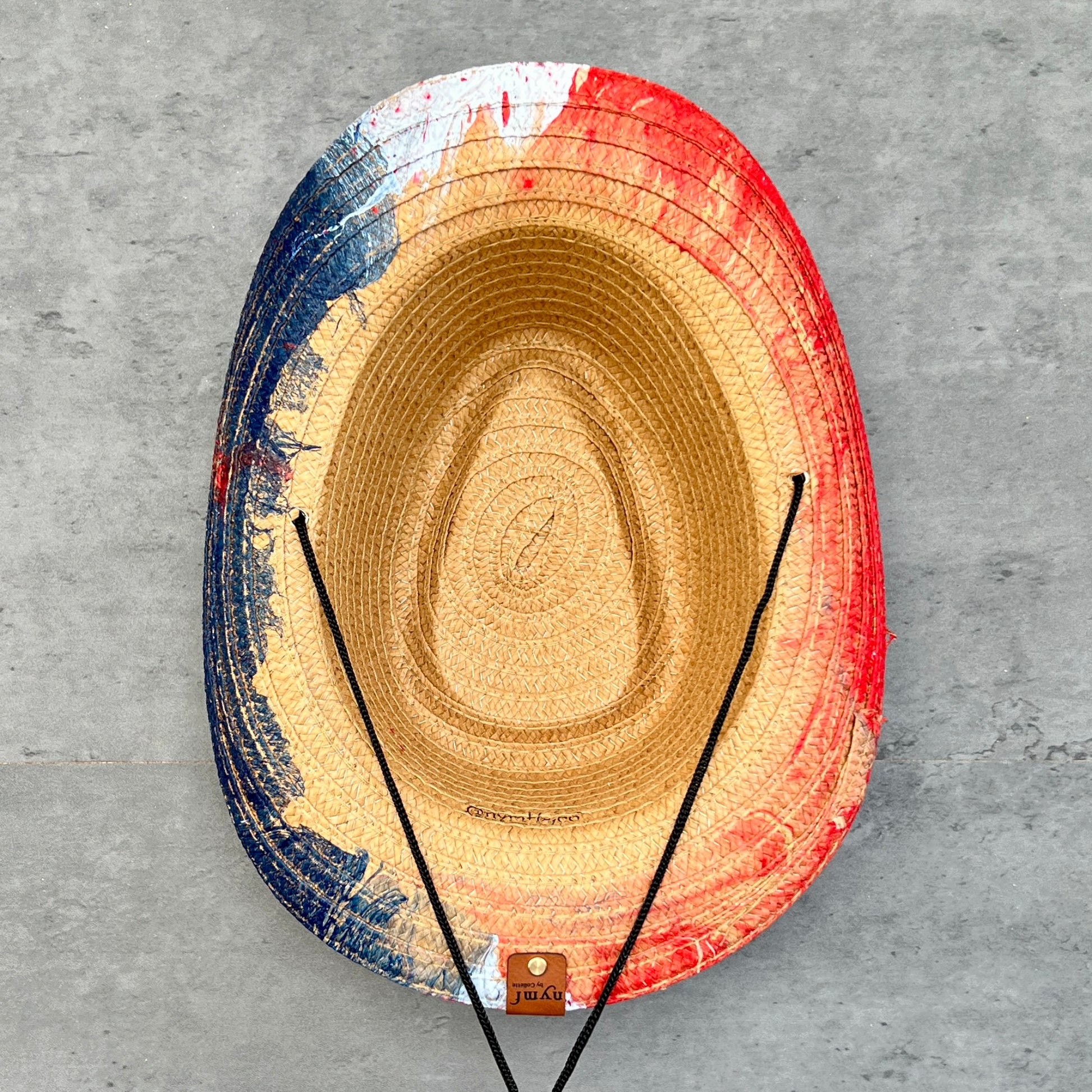Colorful straw hat with a gradient from blue to red on a gray surface