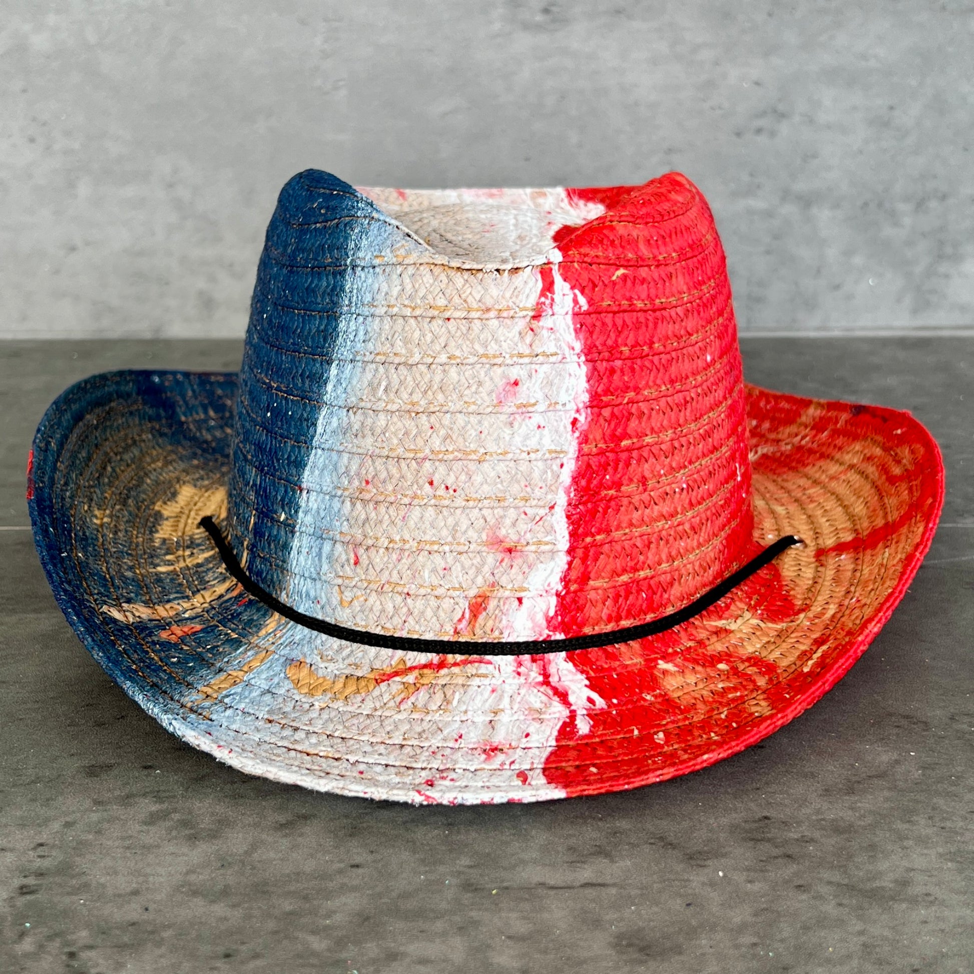 Woven hat with red, white, and blue stripes on a gray surface