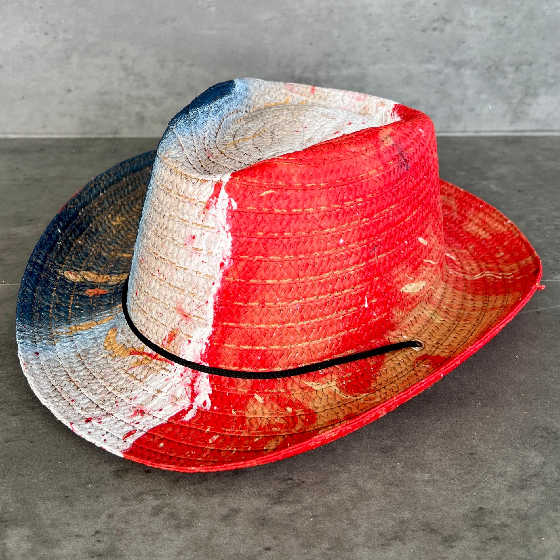 Straw hat with red, white, and blue colors on a gray surface