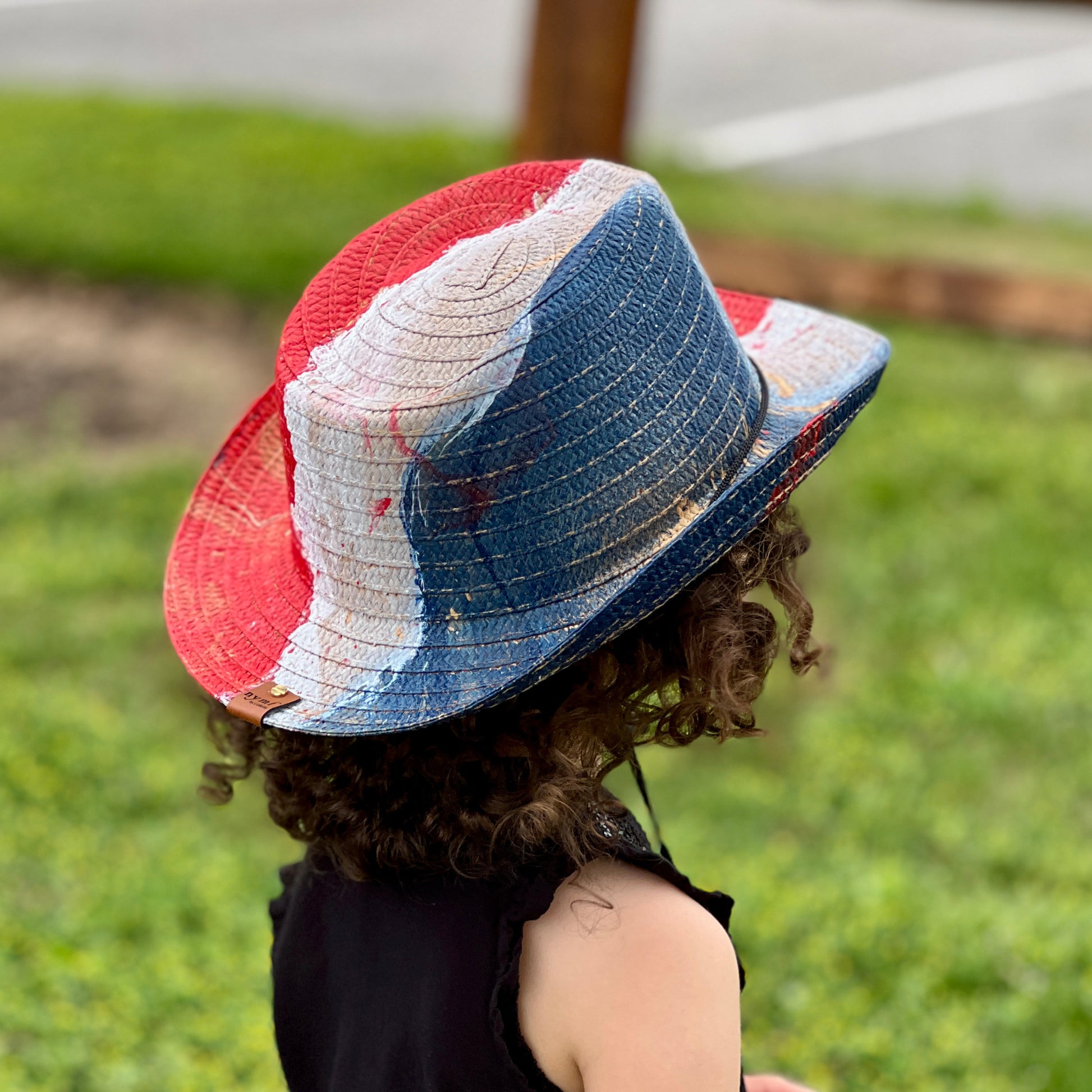 Person wearing a colorful straw hat in an outdoor setting