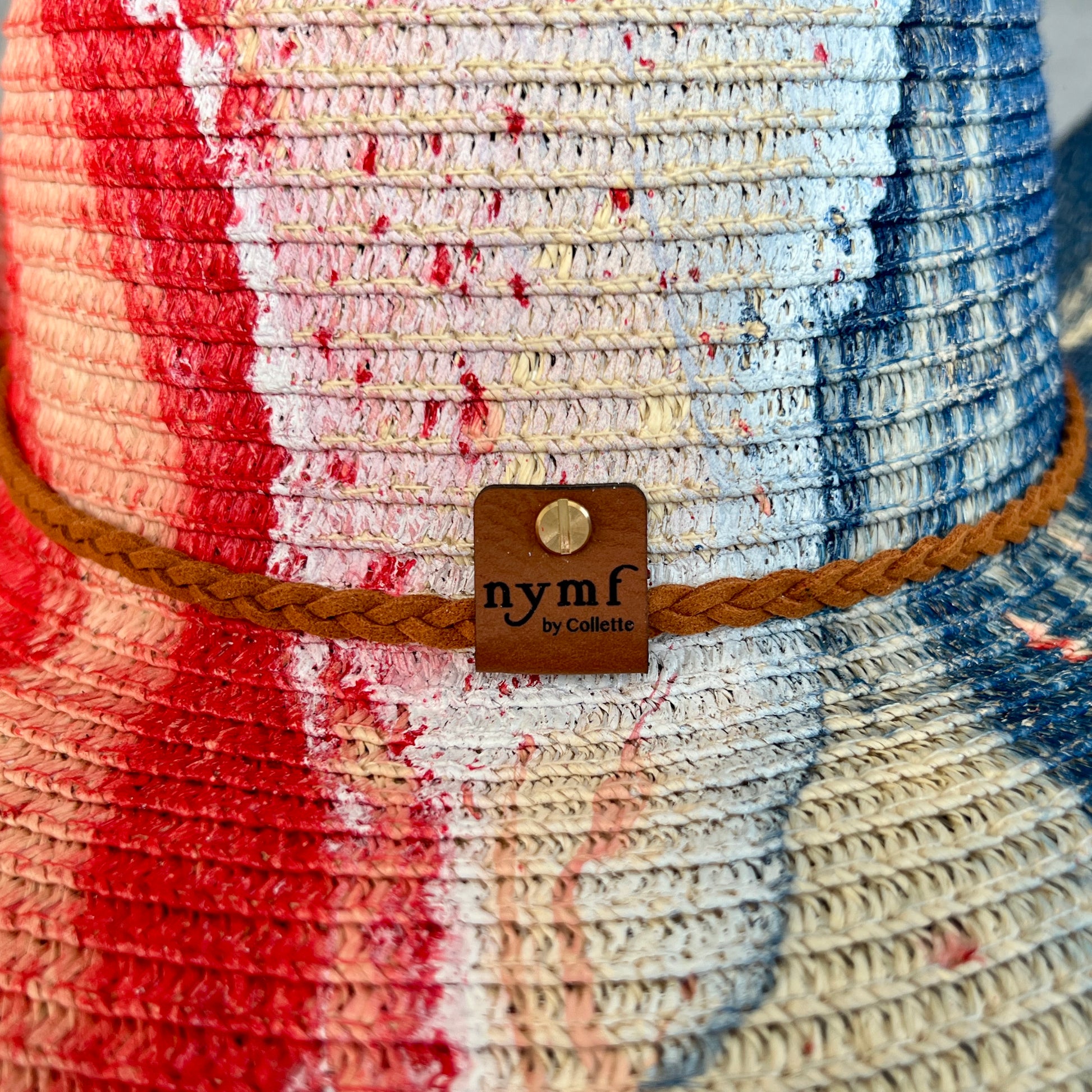 Colorful woven hat with a brand tag labeled 'nymf by Collette'.