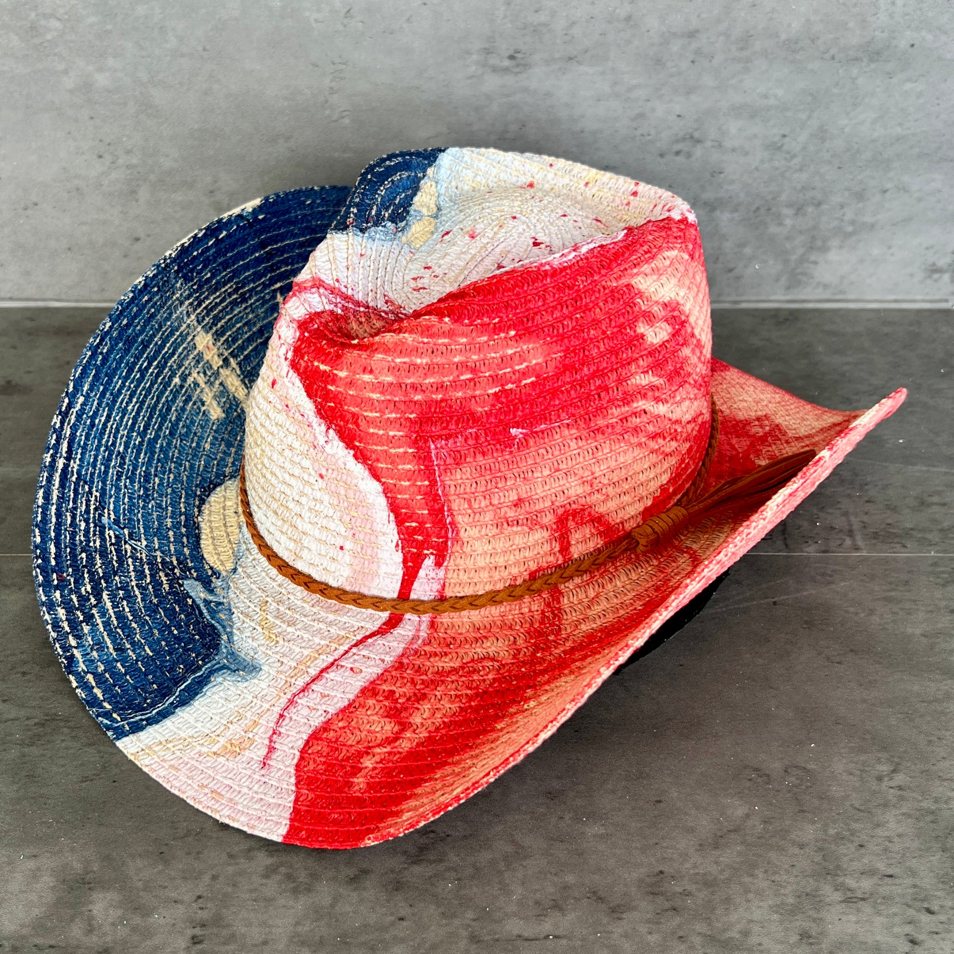 Colorful straw woven hat with red, white, and blue on a gray surface