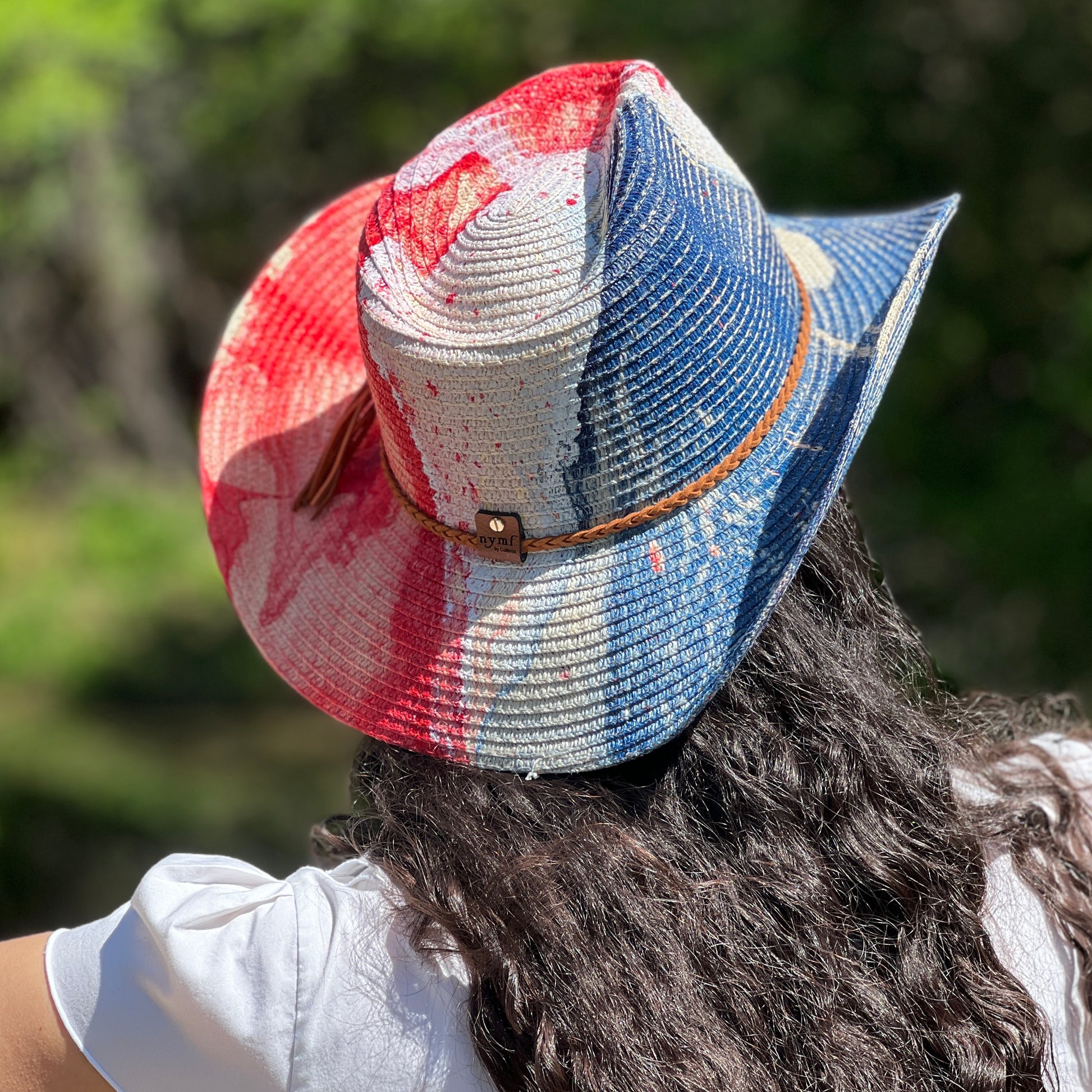 Person wearing a colorful straw hat with a blurred natural background