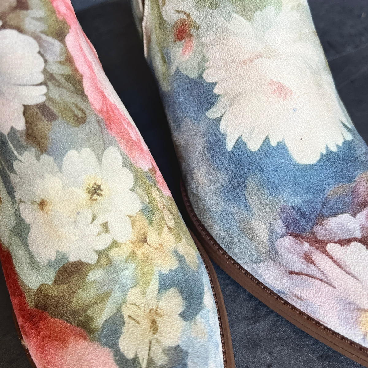 Close-up of blue, pink and cream floral artwork on Rococo suede ankle boots
