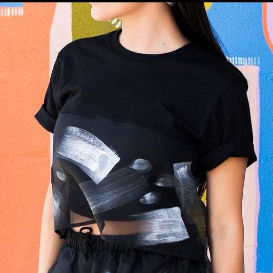 Sheer painted sport crop tee on model gray multi brushstrokes in front of colorful wall mural