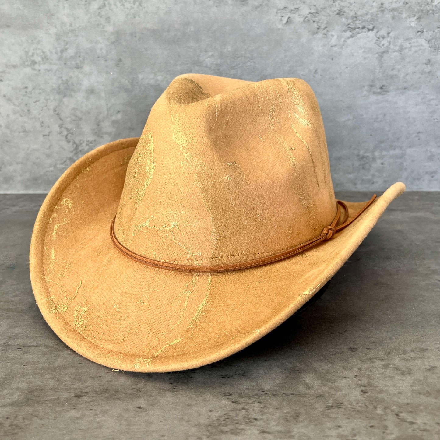 Tan khaki western cowboy hat painted with gold marbling. Has light brown faux suede cord hat band. 