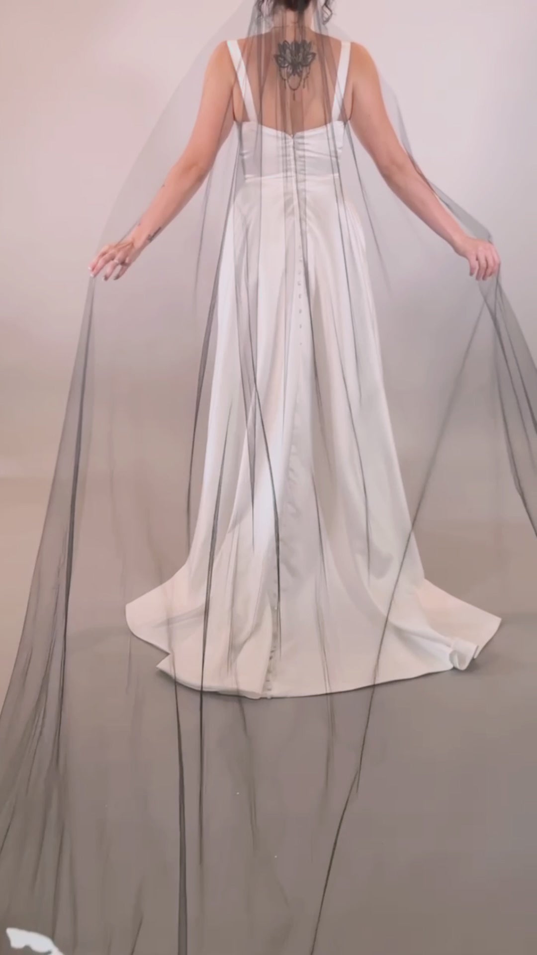 Woman in a white wedding dress with a long black painted veil that says Until Death against a plain background. Video by Taylor Mitchell Model is Isabelle Paulino