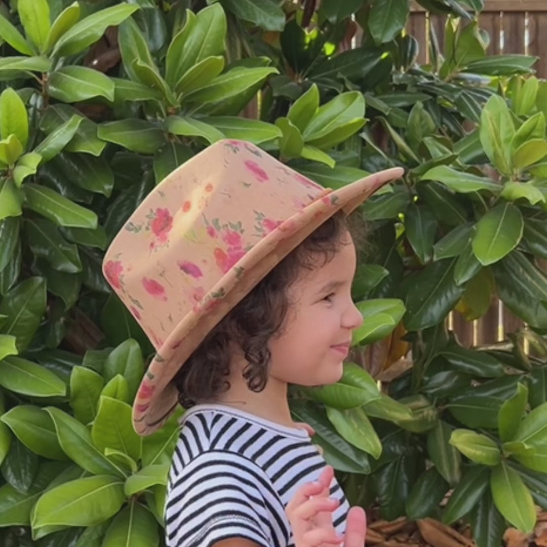 video of child wearing tan cowboy hat with red roses in outdoor background